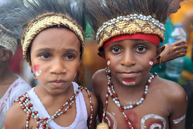 Dua anak mengikuti karnaval budaya dengan mengenakan pakaian adat Papua di Lapangan Yos Sudarso, Agats, Asmat, Papua Selatan, Senin (15/8/2022). Foto: Abdel Syah/Antara Foto