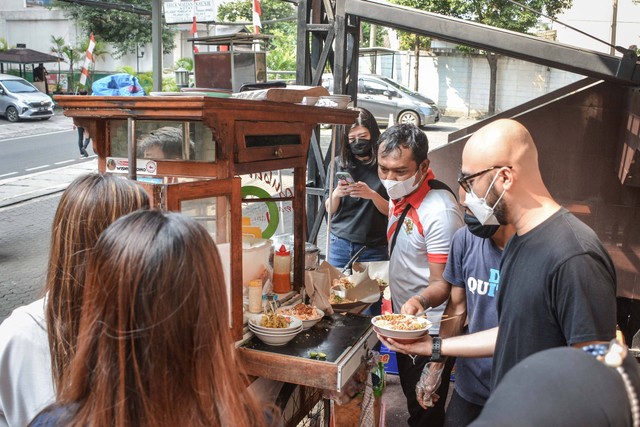 Kholidin alias Bang Udin, atlet parapanahan yang raih medali ASEAN Para Games 2022, sedang menyiapkan bubur dagangannya di parkiran Wisma Geha, Jakarta Pusat, pada Agustus 2022. Foto: Alif Zaky Assidiqi/kumparan