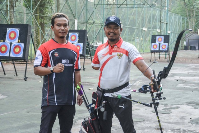 Kholidin alias Bang Udin (kanan), atlet parapanahan yang raih medali ASEAN Para Games 2022, berlatih panahan bersama Coach Denny Decko di Felfest Universitas Indonesia Depok, Jawa Barat, pada Agustus 2022. Foto: Alif Zaky Assidiqi/kumparan