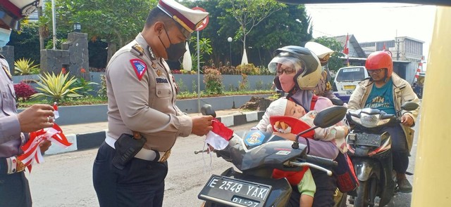 Sat Lantas Polres Kuningan, Polda Jabar, saat memasang bendera merah putih di kendaraan milik warga yang tengah melintas di kawasan Lampu Merah Cijoho, Kuningan. (Andri)