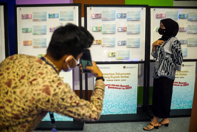 Pengunjung berfoto dengan latar belakan uang kertas di acara Festival Rupiah Berdaulat Bank Indonesia (FERBI) 2022 di GOR Basket Indoor GBK Senayan, Jakarta pada Jumat (19/8). Foto: Iqbal Firdaus/kumparan