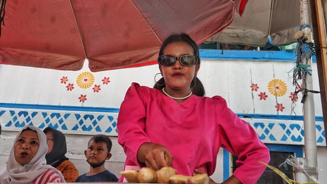 Seorang pedagang jajanan tradisional dengan gaya nyentrik di Festival Bingen Palembang yang digelar di Lr Roda Kecamatan Bukit Kecil Palembang, Minggu (21/8) Foto: abp/Urban Id