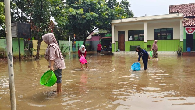 Sejumlah guru dan siswa berlomba menangkap ikan saat banjir menggenangi MI Nurul Islam, Kelurahan Grogol, Kecamatan Limo, Kota Depok. Foto: Dok. Istimewa