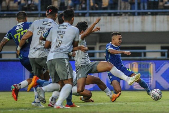 Pesepak bola Persib Bandung Erwin Ramdani (kanan) menendang bola ke arah gawang Bali United pada pertandingan BRI Liga 1 di Stadion Gelora Bandung Lautan Api, Bandung, Jawa Barat, Selasa (23/8/2022). Foto: Raisan Al Farisi/Antara Foto