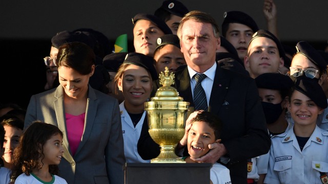 Presiden Brasil Jair Bolsonaro (kanan) dan Ibu Negara Michelle Bolsonaro dikelilingi oleh anak-anak saat mereka berdiri di samping guci berisi hati Dom Pedro I, pendiri dan penguasa pertama Kekaisaran Brasil. Foto: Evaristo Sa/AFP