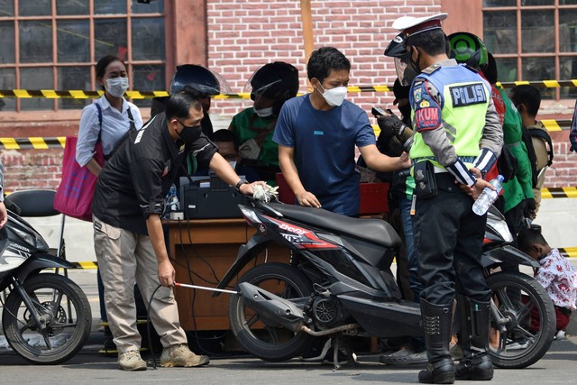 Petugas menguji emisi salah satu sepeda motor milik warga yang melintas di Jalan Kali Besar Barat, Tambora, Jakarta, Kamis (25/8/2022). Foto: Aditya Pradana Putra/ANTARA FOTO