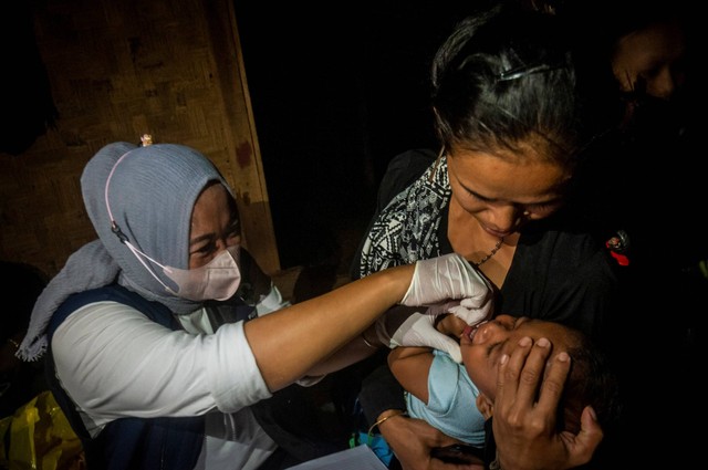 Bidan Puskesmas Cisimeut memberikan vaksin polio kepada seorang anak Suku Baduy di Kampung Cisadane, Lebak, Banten, Jumat (26/8/2022) malam. Foto: Muhammad Bagus Khoirunas/ANTARA FOTO