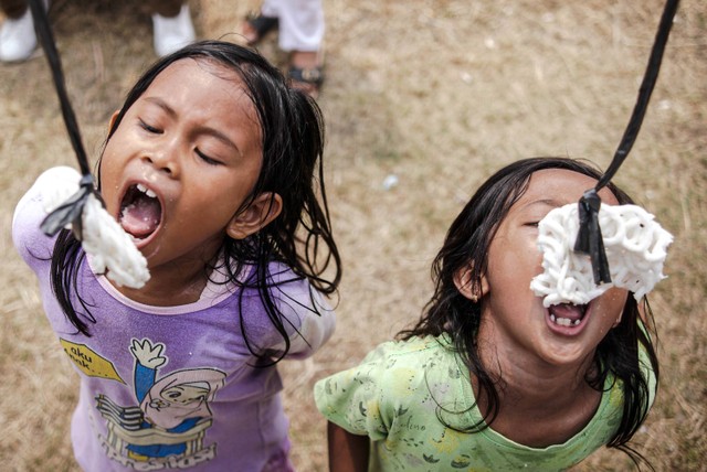 Warga mengikut lomba makan kerupuk di bawah Jalan Tol Becakayu, Cipinang Melayu, Kalimalang, Jakarta Timur, Sabtu (27/8/2022). Foto: Jamal Ramadhan/kumparan