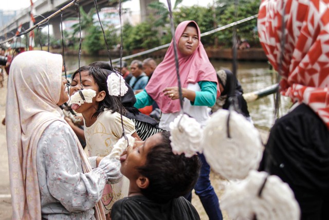 Warga mengikut lomba makan kerupuk di bawah Jalan Tol Becakayu, Cipinang Melayu, Kalimalang, Jakarta Timur, Sabtu (27/8/2022). Foto: Jamal Ramadhan/kumparan