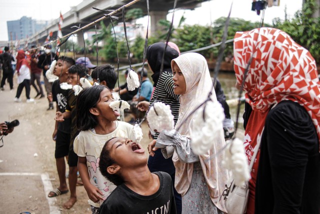 Warga mengikuti lomba makan kerupuk di bawah Jalan Tol Becakayu, Cipinang Melayu, Kalimalang, Jakarta Timur, Sabtu (27/8/2022). Foto: Jamal Ramadhan/kumparan