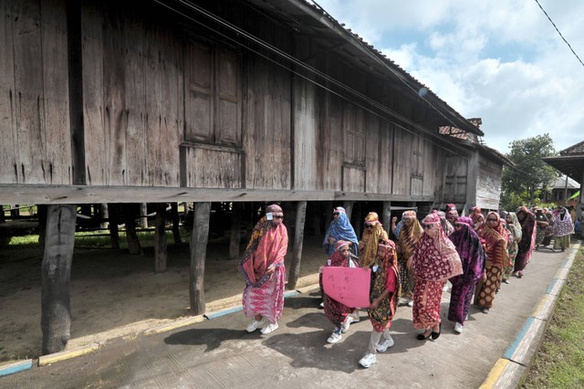 Peserta pawai berjalan sambil mengenakan tutup kepala tradisional perempuan Melayu Seberang Kota Jambi pada Festival Tudung Lingkup di Kampung Tengah, Pelayangan, Jambi, Minggu (28/8/2022). Foto: Wahdi Septiawan/ANTARA FOTO