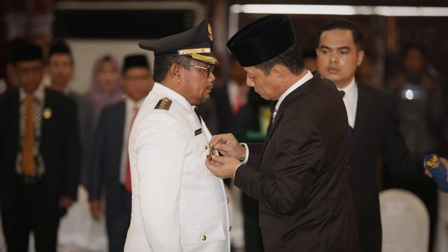 Achmad Marzuki memasang lencana kepada Pj Wali Kota Langsa, Said Mahdum Majid dalam pelantikan. Foto: Abdul Hadi/acehkini