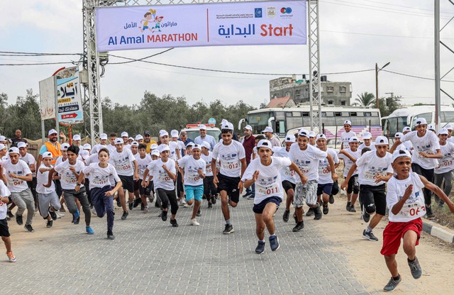 Pemuda Palestina berkompetisi dalam Marathon Al-Amal (Harapan) di Khan Yunis di Jalur Gaza selatan, pada Minggu (28/8/2022). Foto: Said Khatib/AFP