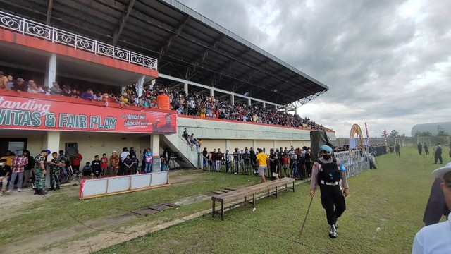 Sejumlah penonton terpaksa harus menonton dari di pinggir lapangan karena kondisi tribun Stadion Sports Center Pangkalan Bun disesaki penonton. Foto: Lukman Hakim/InfoPBUN