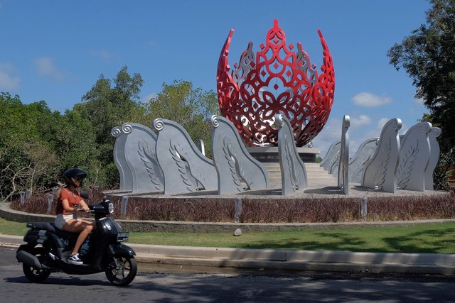 Wisatawan yang mengendarai sepeda motor melintas di dekat monumen G20 yang baru dibangun di Denpasar, Bali, Jumat (2/9/2022). Foto: Nyoman Hendra Wibowo/Antara Foto
