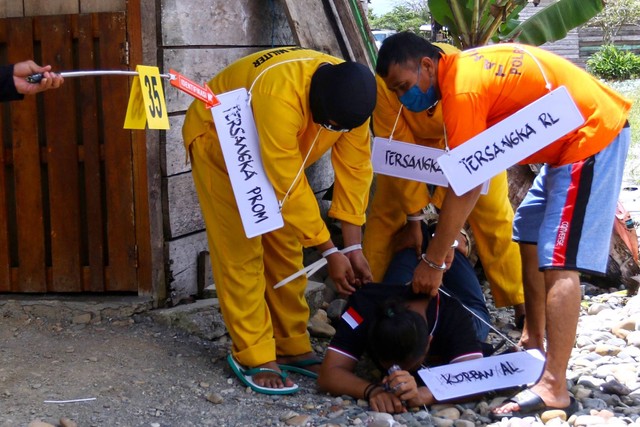 Tiga tersangka melakukan adegan saat mengikuti rekonstruksi pembunuhan dan mutilasi empat warga di Timika, Papua, Sabtu (3/9/2022). Foto: Sevianto Pakiding/ANTARA FOTO
