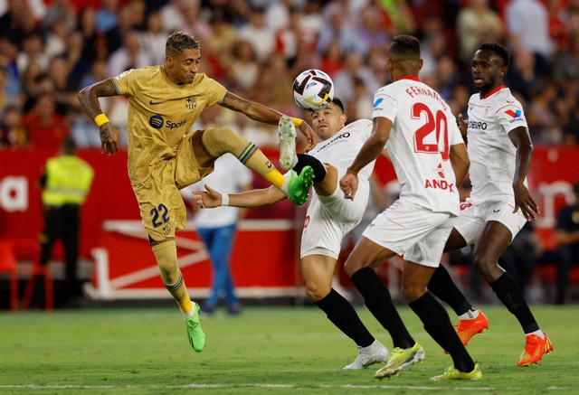 Pemain FC Barcelona Raphinha duel dengan Marcos Acuna dari Sevilla saat pertandingan di Ramon Sanchez Pizjuan, Seville, Spanyol, Sabtu (3/9/2022). Foto: Marcelo Del Pozo/Reuters