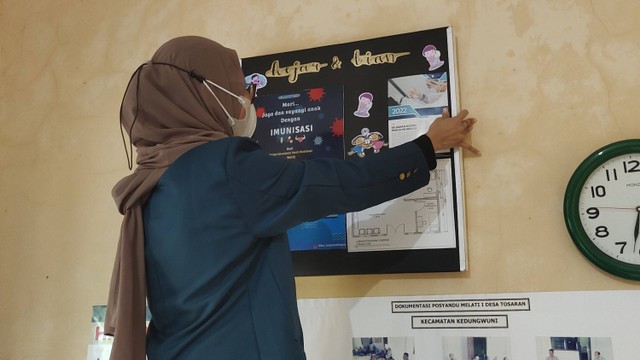 Pemasangan Mading pada dinding Ruangan Posyandu Melati I Desa Tosaran (Selasa, 23/8/2022). Foto: Kinanti Dianing Pramudya Wardhani