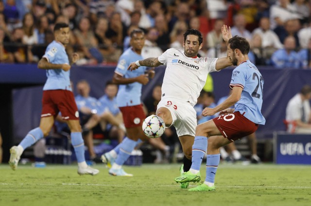 Pemain Manchester City Bernardo Silva duel dengan pemain Sevilla Isco saat pertandingan di Ramon Sanchez Pizjuan, Seville, Spanyol, Selasa (6/9/2022). Foto: Marcelo Del Pozo/Reuters