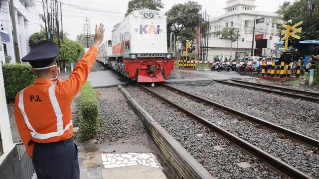 Penjaga Jalan Lintasan (PJL) yang sedang mengatur perlintasan kereta api. Foto: KAI