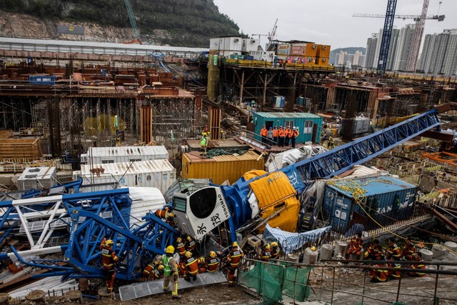Anggota tim Urban Search And Rescue (USAR) (C) bekerja dengan derek di lokasi konstruksi yang runtuh, Hong Kong, Rabu (7/9/2022). Foto: Isaac Lawrence/AFP