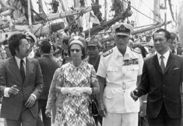 Ratu Inggris Elizabeth II dan Earl Mountbatten, berseragam angkatan laut putih, didampingi Gubernur Jakarta Ali Sadikin, kanan, berjalan-jalan di sepanjang dermaga di Sunda Kelapa, pada 19 Maret 1974. Foto: AP Photo