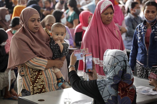 Petugas memotret warga penerima Bantuan Langsung Tunai (BLT) Bahan Bakar Minyak (BBM) dan Bantuan Program Sembako di Kantor Pos Pusat Batam Centre, Batam, Kepulauan Riau, Kamis (8/9/2022). Foto: Teguh Prihatna/Antara Foto