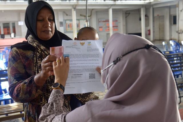 Petugas menyalurkan Bantuan Langsung Tunai (BLT) Bahan Bakar Minyak (BBM) dan Bantuan Program Sembako kepada warga di Kantor PT Pos Indonesia (Persero), Banda Aceh, Aceh, Jumat (9/9/2022). Foto: Ampelsa/Antara Foto