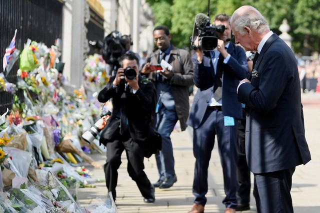 Raja Inggris Charles memberi isyarat didepan karangan bunga bela sungkawa atas meninggalnya Ratu Elizabeth II, di luar Istana Buckingham, di London, Inggris, Jumat (9/9/2022). Foto: Toby Melville/REUTERS