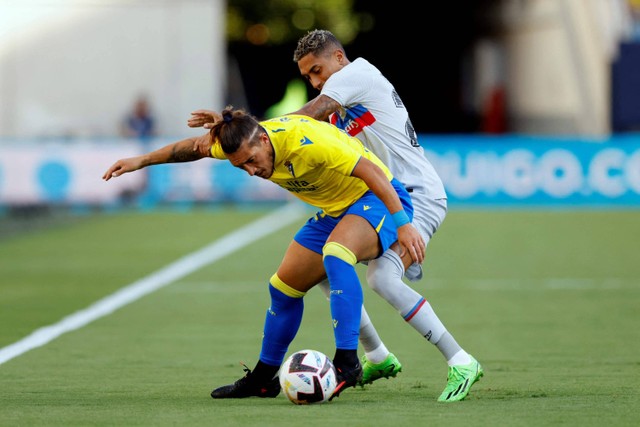 Pemain FC Barcelona Raphinha berebut bola dengan pemain Cadiz pada pertandingan lanjutan Liga Spanyol di Estadio Nuevo Mirandilla, Cadiz, Spanyol. Foto: Marcelo Del Pozo/REUTERS