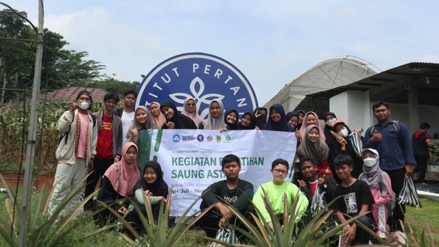 Kegiatan foto bersama tim PPK Ormawa dengan pemuda Saung Astani Desa Benteng di depan logo IPB Kebun Sadifa. Foto: PPK Ormawa DPM FEM