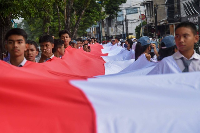 Sejumlah peserta membentangkan bendera merah putih di kawasan Jalan Brigjend Katamso, Medan, Sumatera Utara, Selasa (13/9/2022). Foto: Fransisco Carolio/ANTARA FOTO