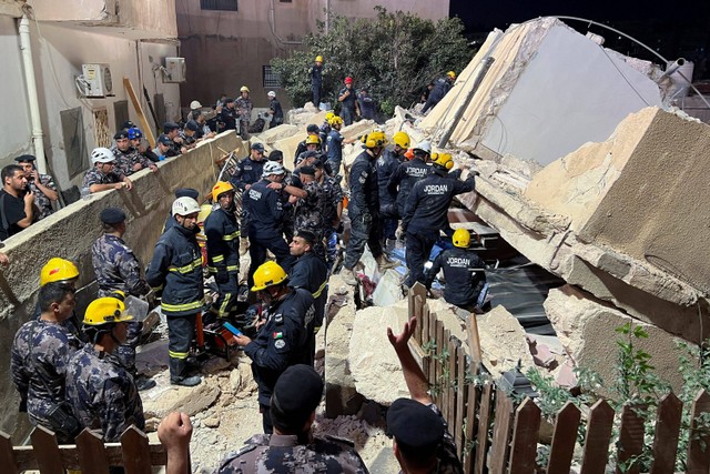 Anggota pertahanan sipil bekerja di lokasi robohnya bangunan tempat tinggal empat lantai di Amman, Yordania. Foto: Jehad Shelbak/REUTERS