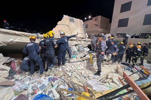 Anggota pertahanan sipil bekerja di lokasi robohnya bangunan tempat tinggal empat lantai di Amman, Yordania. Foto: Jehad Shelbak/REUTERS