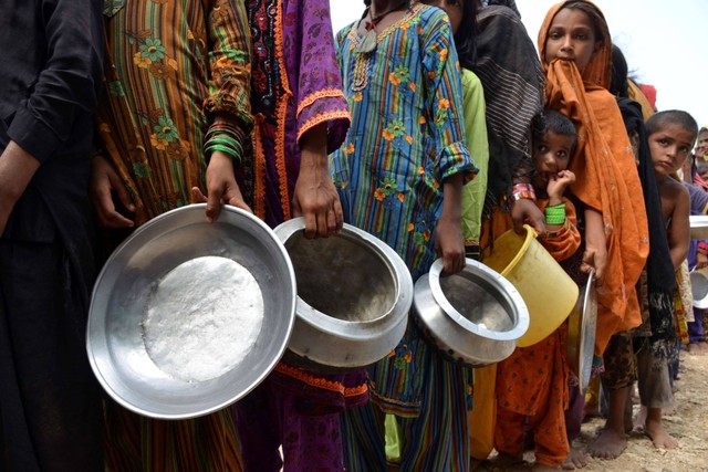 Pengungsi yang terkena dampak banjir berdiri dalam antrean untuk menerima makanan yang didistribusikan oleh Saylani Welfare Trust di sebuah kamp darurat di Sehwan, Sindh, Selasa (13/9/2022). Foto: Husnain Ali/AFP