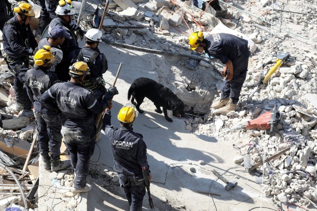 Tim penyelamat dengan bantuan anjing pelacak mencari korban di lokasi bangunan runtuh di Amman, Yordania. Foto: Alaa Al Sukhni/REUTERS