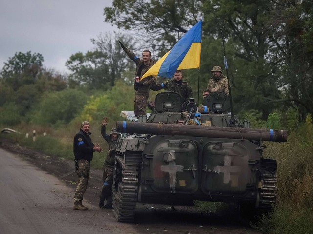 Anggota layanan Ukraina berdiri di atas kendaraan tempur infanteri BMP-1, di tengah serangan Rusia terhadap Ukraina, dekat kota Izium, yang baru-baru ini dibebaskan oleh Angkatan Bersenjata Ukraina, di wilayah Kharkiv, Ukraina, Rabu (14/9/2022). Foto: Gleb Garanich/Reuters