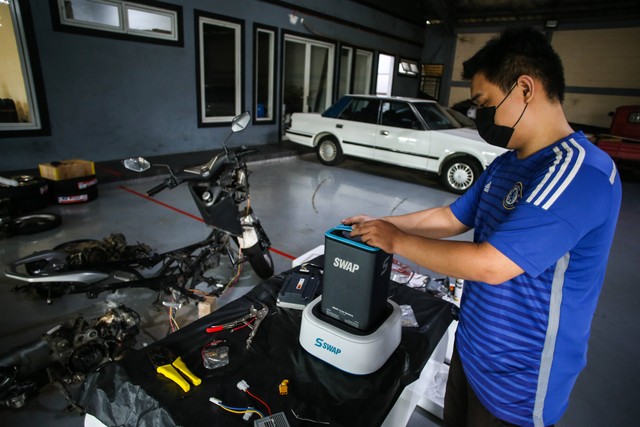 Pekerja mengisi ulang baterai saat mengonversi sepeda motor konvensional menjadi sepeda motor listrik di Lengkong, Tangerang Selatan, Banten, Kamis (15/9/2022). Foto: Rivan Awal Lingga/ANTARA FOTO