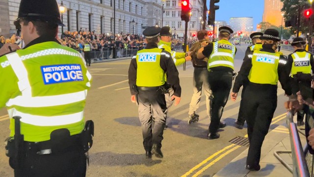 Petugas polisi menahan seorang pria yang sedang bermain sepatu roda di jalan mobil Raja Charles III di London, Inggris, Jumat (16/9/2022). Foto: Ursula Petula Barzey/via REUTERS