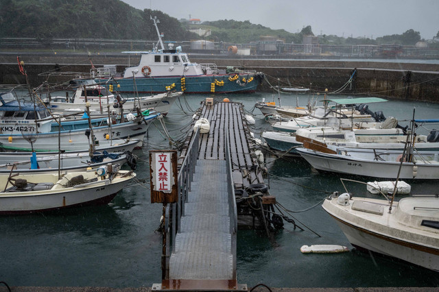 Perahu nelayan terlihat ditambatkan saat hujan turun dari pola cuaca yang disebabkan oleh Topan Nanmadol di pelabuhan di Minamata, prefektur Kumamoto, Jepang, Minggu (18/9/2022). Foto: YUICHI YAMAZAKI/AFP