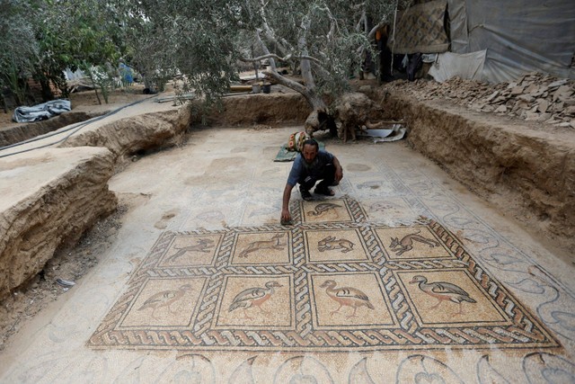 Petani Palestina Salman al-Nabahin membersihkan lantai mosaik berasal dari era Bizantium  di Jalur Gaza. Foto: Ibraheem Abu Mustafa/REUTERS