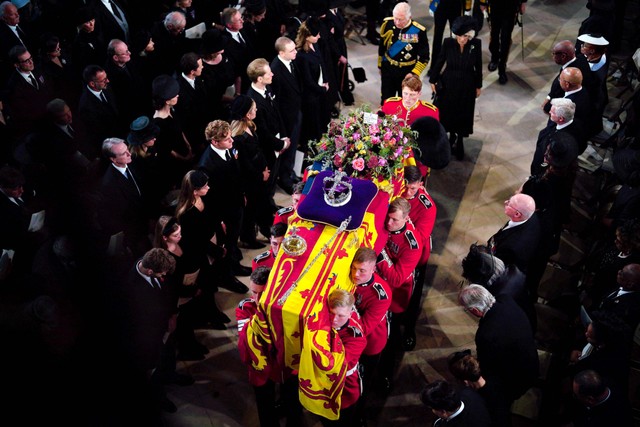 Pengawal Grenadier Batalyon 1 membawa peti mati Ratu Elizabeth II, dibungkus dengan Standar Kerajaan dan dihiasi dengan Mahkota Negara Kekaisaran dan bola serta tongkat kerajaan di dalam Kapel St George di Kastil Windsor. Foto: Ben Birchall / POOL / AFP