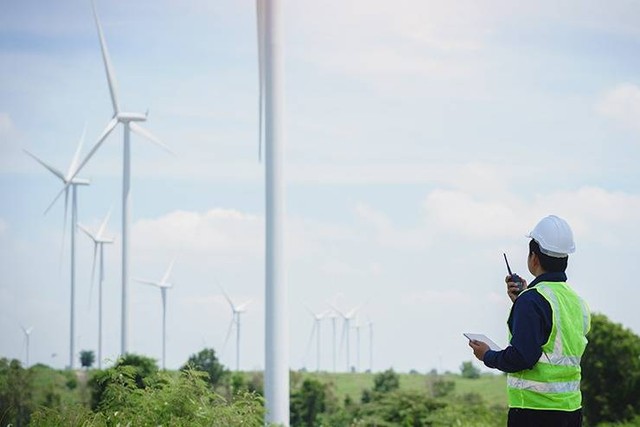 Ilustrasi. Seorang insinyur sedang memegang tablet di depan pembangkit listrik tenaga angin yang sedang menghasilkan listrik, konsep pembangunan keberlanjutan melalui energi alternatif. Foto: @arrow_smith2 | Freepik. 