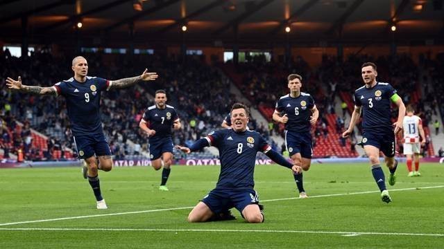 Pemain Skotlandia Callum McGregor berselebrasi dengan rekan setimnya, di Stadion Hampden Park, Glasgow, Skotlandia, Inggris, Selasa (22/6). Foto: Pool via REUTERS/Paul Ellis