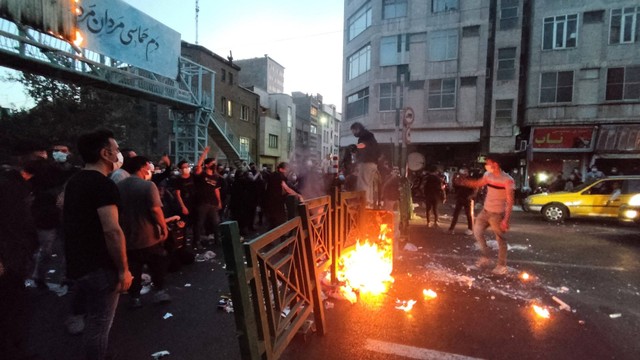 Massa menyalakan api selama protes atas kematian Mahsa Amini, seorang wanita yang meninggal setelah ditangkap oleh 'polisi moral' republik Islam, di Teheran, Iran, Rabu (21/9/2022. Foto: WANA via REUTERS