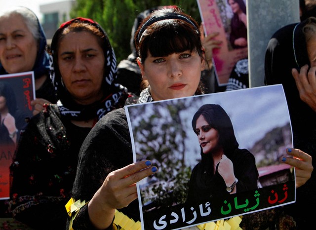 Seorang wanita memegang plakat selama protes menyusul kematian Mahsa Amini di depan markas besar PBB di Erbil, Irak, Sabtu (24/9/2022). Foto: Azad Lashkari/REUTERS