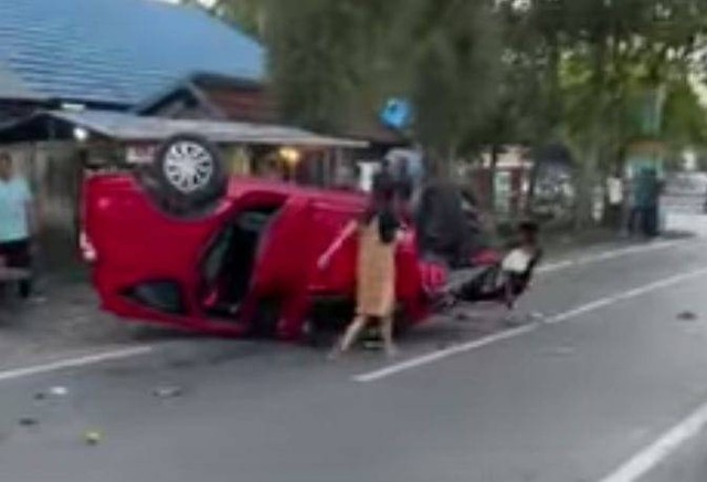 Kondisi mobil Sigra berwarna merah terbalik usai menabrak lima sepeda motor dan gerobak sate.