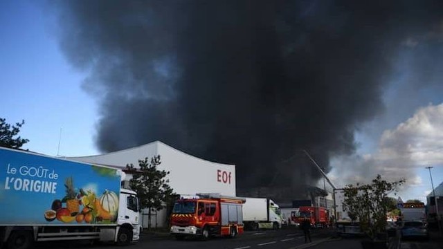 Asap hitam mengepul ke langit saat petugas pemadam kebakaran bekerja untuk memadamkan api di sebuah gedung di pasar grosir makanan "Rungis International Market" di Rungis, selatan Paris, Prancis, Sabtu (25/9/2022). Foto: Christophe Archambault/AFP