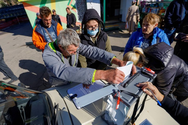 Penduduk setempat memberikan suaranya ke dalam kotak suara pada hari ketiga referendum tentang bergabungnya Republik Rakyat Donetsk ke Rusia, di Mariupol, Ukraina, Minggu (25/9/2022). Foto: Alexander Ermochenko/REUTERS