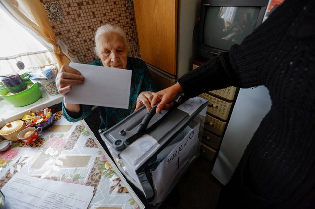 Penduduk lokal Valentina, memberikan suaranya saat petugas menghampiri apartemennya, pada hari ketiga referendum tentang bergabungnya Republik Rakyat Donetsk ke Rusia, di Mariupol, Ukraina, Minggu (25/9/2022). Foto: Alexander Ermochenko/REUTERS